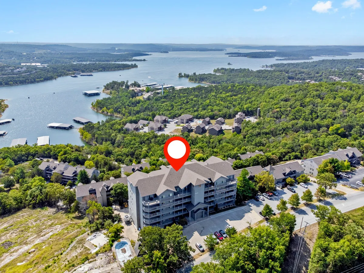 A tranquil view of Table Rock Lake with a building in the foreground, surrounded by lush greenery. Boats are visible on the water, suggesting opportunities for boating, fishing, and lakeside picnics.