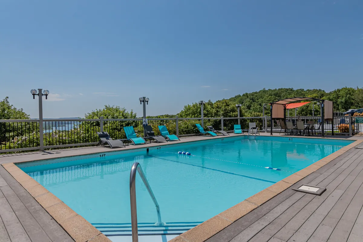 A sparkling outdoor swimming pool surrounded by lounge chairs, with a beautiful landscape view in the background. The scene is lit by a gentle sunset, creating a leisurely and refreshing atmosphere ideal for families unwinding together.