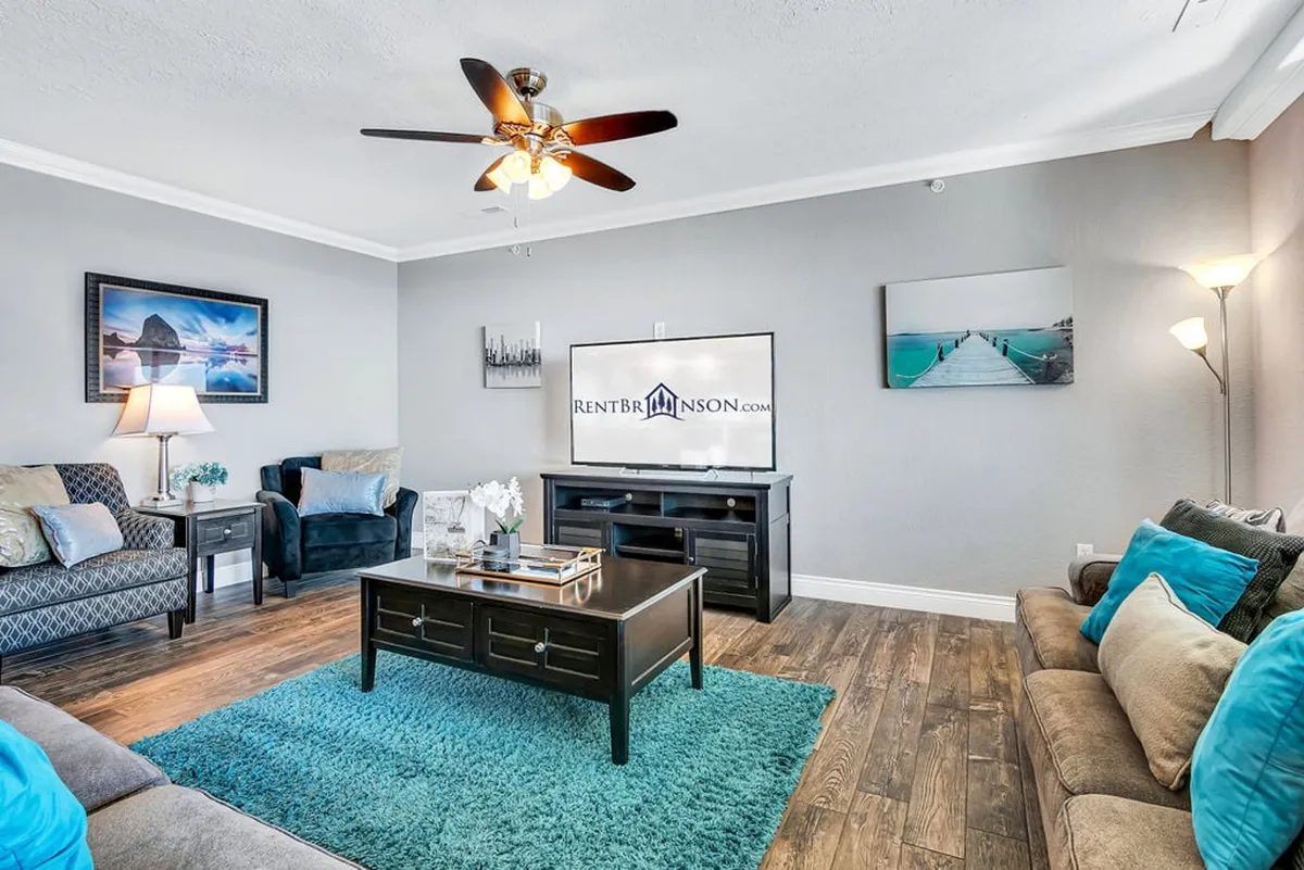 A comfortable living area with a sofa, coffee table, TV, elegant artwork, and a cozy lamp. The space is arranged for relaxation or gathering, and its versatile layout suggests the presence of a sleeper sofa for additional guests.