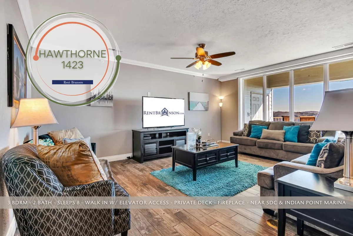 A cozy living room with a plush sofa accented with decorative cushions, a coffee table, and a television. Large windows bring in abundant natural light, creating a relaxed atmosphere ideal for movie nights, game nights, and socializing while enjoying the scenery outside.